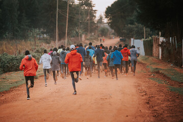 Group of runners on a morning mass training in Kenya. Africans running on red roads in iten city. Running preparation for marathon races