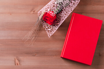 Red rose and red book on pink background, Sant Jordi holiday card