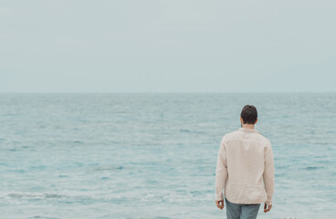 Man standing on the beach and looking at the ocean