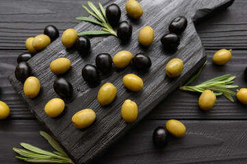Black and green olives on a dark wooden black background.