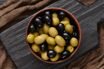 Black and green olives on a dark wooden black background.