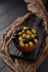 Black and green olives on a dark wooden black background.