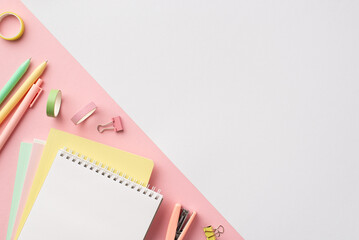 School supplies concept. Top view photo of colorful stationery diaries pens adhesive tape binder clips and mini stapler on bicolor white and pink background with copyspace
