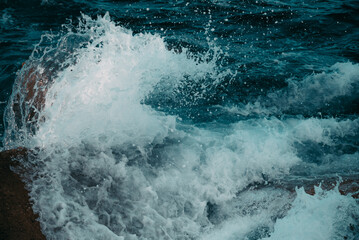 Close-up of water splashes against the breakwaters on the Balearic Sea. View from the pier on the beach of Barcelona, Spain.