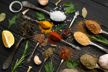 Colorful various herbs and spices for cooking on dark wooden rustic background