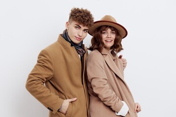 a man and a woman posing on a white background in an autumn coat put their hands in their pockets and sweaters, gently looking forward
