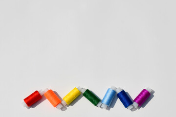 Spools of sewing thread of seven colors of the rainbow close-up on a light background