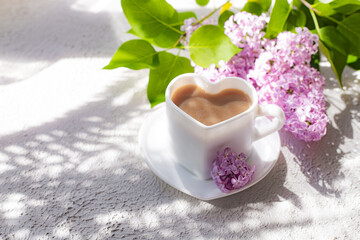 Cappuccino coffee in a cup and a branch of lilac on a white background with shadows . A hot drink. relax. The concept of cafeteria advertising. Article about cappuccino. Making cappuccino. Lilac branc
