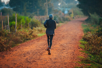 A lone runner trains in Kenya. A marathon runner runs on red soil in the city of Iten, home of...