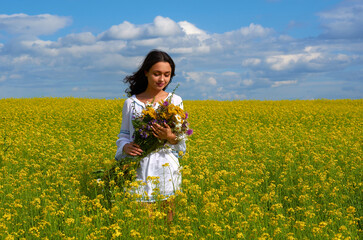 Fototapeta premium a girl in the national costume of Ukraine in a field of flowers