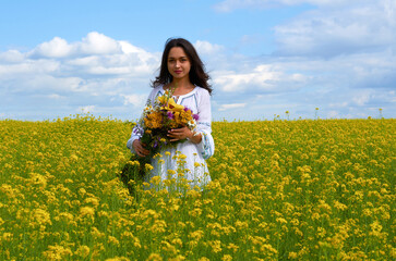 Fototapeta premium a girl in the national costume of Ukraine in a field of flowers