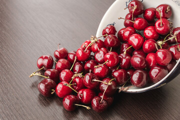 Sweet cherries with drops of water spilling out from the bowl. Cherry organic berries harvest - healthy eating and food concept