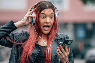 amazed redhead girl with mobile phone and earphones