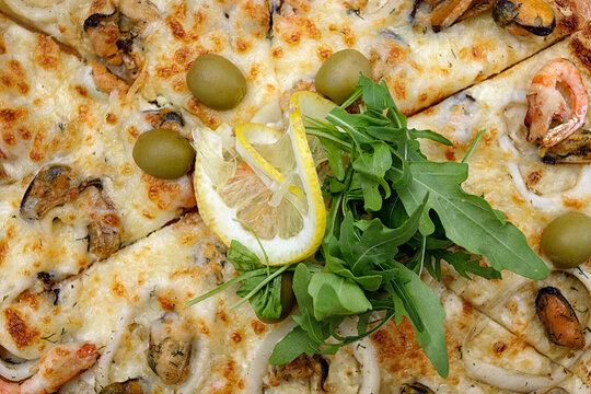 Marinara pizza with squid mussels shrimp olives and lemon. top view. Closeup