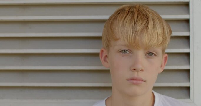 Close-up portrait of a cute teen boy looking at the camera. Space for text grey background.