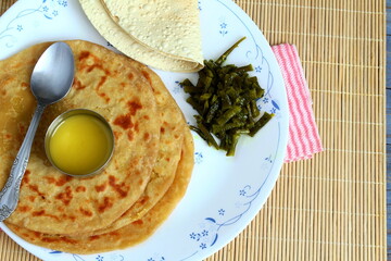 indian gujarati traditional sweet stuffed flatbread or sweet roti vedmi also known in india as holige,puran poli served with pure cows ghee clarified butter and papad