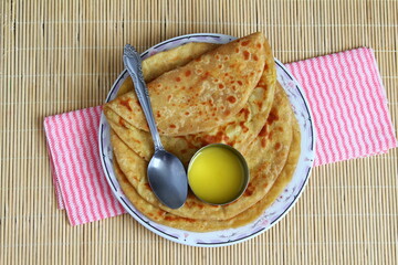 indian gujarati traditional sweet stuffed flatbread or sweet roti vedmi also known in india as holige,puran poli served with pure cows ghee clarified butter and papad - obrazy, fototapety, plakaty