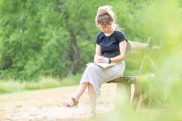 Young woman sitting on a bench reading the Bible