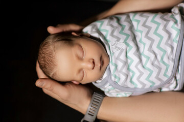 newborn baby in the arms of dad on a black background