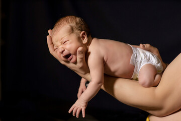 Fototapeta na wymiar newborn baby in the arms of dad on a black background