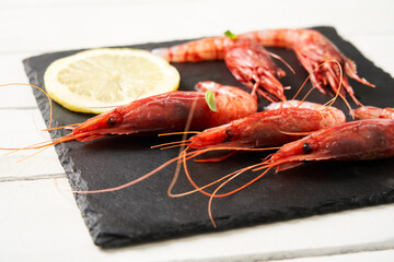 Delicious shrimp with cajun seasoning and lime on a black plate. Food concept. Italian food. Seafood. Front view.