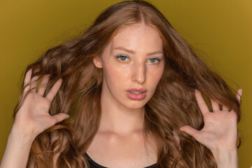 Fototapeta premium Beautiful sexy woman with red well groomed long curly hair with braces without makeup looking at camera on isolated background