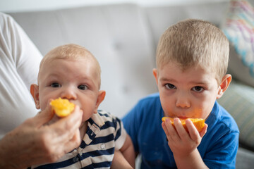 Hermanos comiendo naranja juntos mirando a la cámara