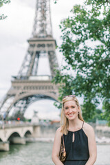 Blonde 30-something woman smiles in front of the Eiffel Tower in Paris