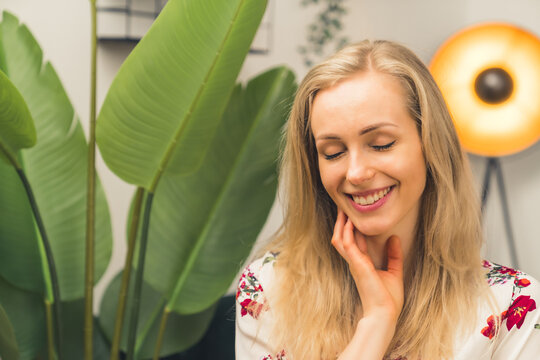 Caucasian Blonde Smiling girl in a room with a plant. High quality photo