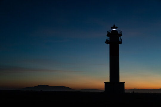 Lighthouse silhouette in Delta de l'ebro Spain during the sunset