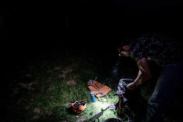 man preparing a backpack at night with frontal light