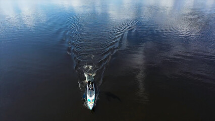 Top view of a man practising on a surfboard with a rowing paddle in the lake, sport and lifestyle...