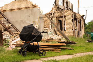 A baby stroller against the background of the destroyed village house after the bombing. Russia's...