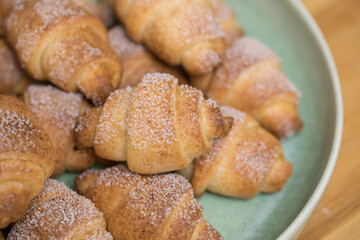 Homemade croissants bagels with sugar powder on blue plate in bowl on wooden table bakery fresh tasty food