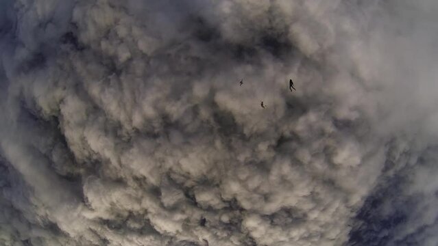 a group of parachutists fall into the clouds at sunset
