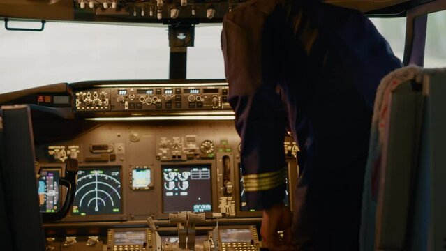 African american captain inserting destination coordinates to help pilot before takeoff, flying airplane with dashboard command. Using control panel buttons, windscreen compass and radar.