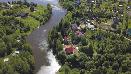 Aerial view of a town with many green trees located along the river in a sunny summer day. Clip....