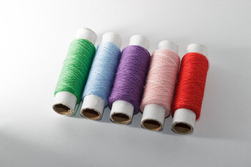 Green, grey, pink and purple threads on the white background