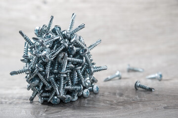 Ball of steel screws on the wooden background. Magnetized steel screws