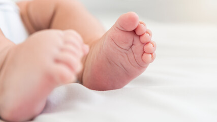 Obraz na płótnie Canvas Close up little tiny baby with chubby foots over a sheets bed. Peace calm infant
