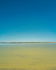 Tranquil minimalistic landscape of the blue sky, horizon, and warm glowing water of Chaplin Lake, the salt lake, in Canada
