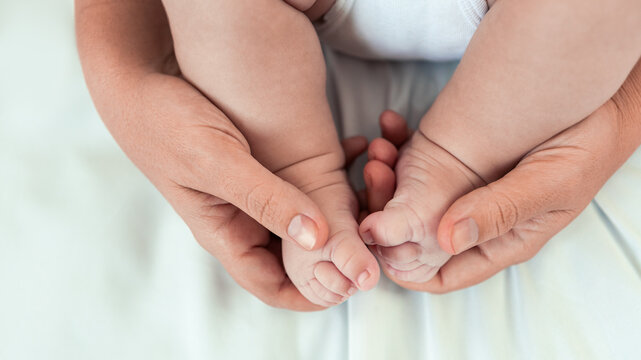 Mom hands holding newborn legs. Beautiful conceptual image motherhood and baby