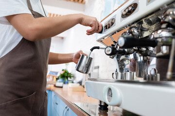 Cropped view of african american barista in apron making coffee in confectionery.