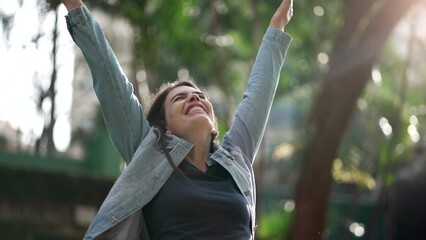Happy woman celebrating achievement raising arms in the air feeling FREEDOM. Joyful person standing outside in nature