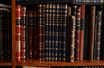 closeup of old Hebrew Jewish books or seforim on a wooden bookshelf, bookcase in jewish library...