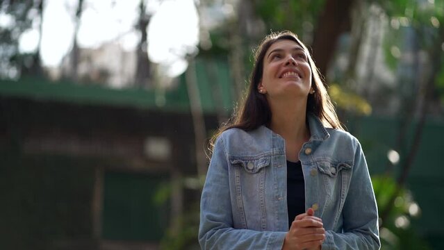 Happy woman standing at park looking at sky smiling. Satisfied thankful person celebrating life
