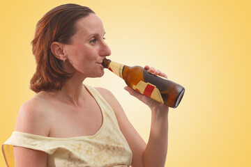 Young woman in rumpled clothes drinking beer from a bottle. Female alcoholism