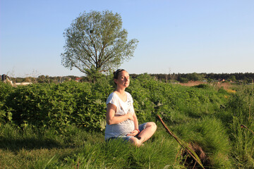 Naklejka na ściany i meble Pregnant woman sitting on the grass