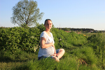 Pregnant woman sitting on the grass