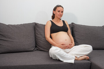 Pregnant woman sitting on the grey sofa